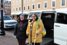 An image of two women standing next to an accessible minivan on a brick sidewalk.