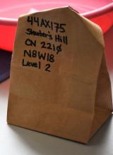 A paper bag with artifacts inside is labeled with the exact location, or provenience, information.