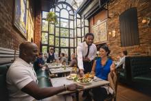 couple at restaurant eating with waiter serving food