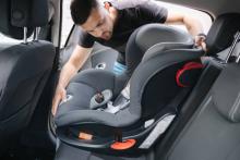 Adult Man Placing Car Seat in Back Seat of a Vehicle