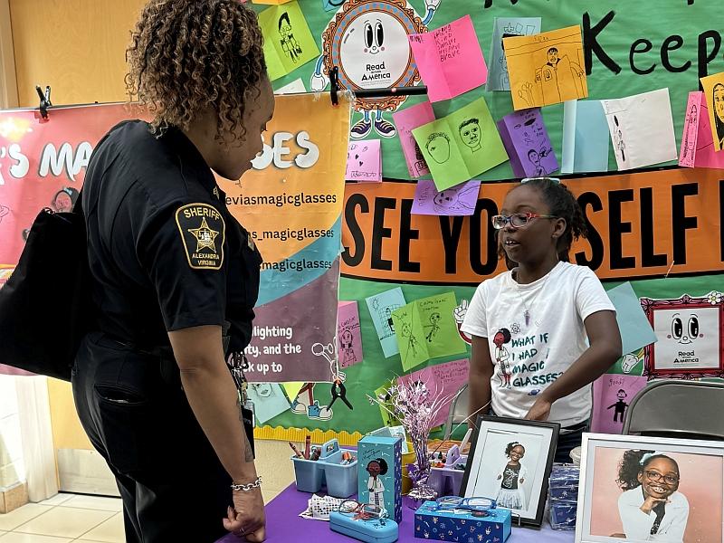 Deputy sheriff speaking with young author about her book at a school event